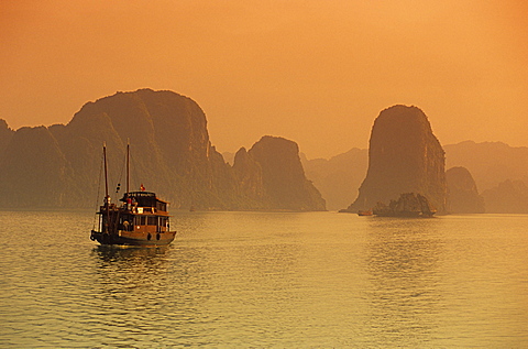 Traditional boat sailing through limestone archipelago at sunset, Ha Long Bay, UNESCO World Heritage Site, Northeast, Vietnam, Indochina, Southeast Asia, Asia